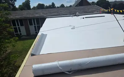 TPO membrane being rolled out over new cover board on a church flat roof