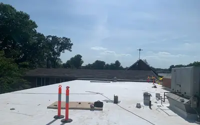 Completed white TPO membrane roof on a church with the steeple and rooftop HVAC unit in view
