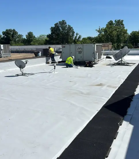 Crew flashing rooftop HVAC units on a freshly installed white TPO roof