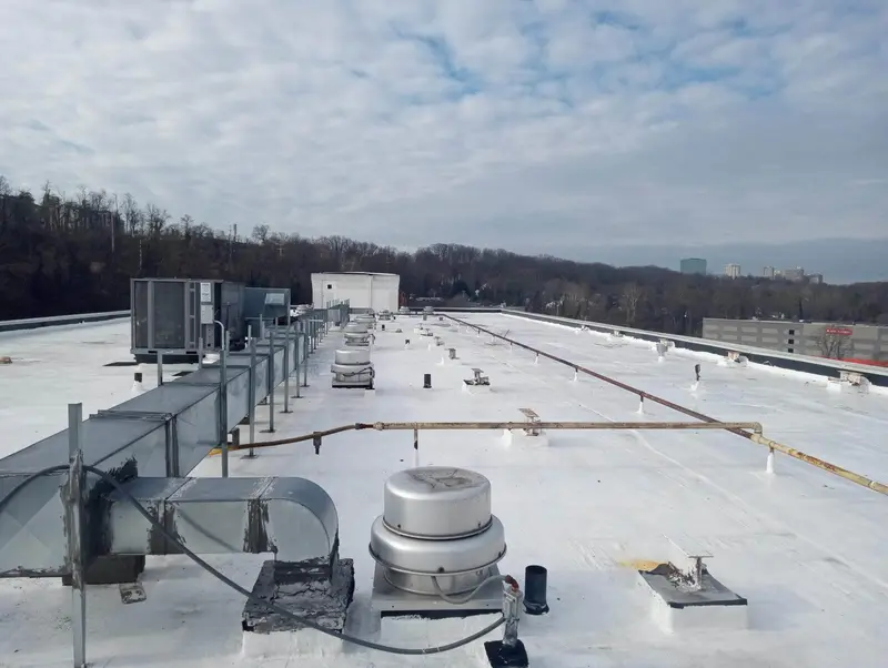 Flat commercial roof with HVAC units, ventilation, and piping after repair