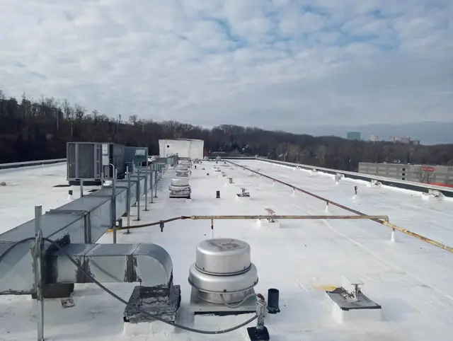 Flat commercial roof with HVAC units, ventilation, and piping
