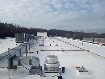 Flat commercial roof with HVAC units, ventilation, and piping after repair