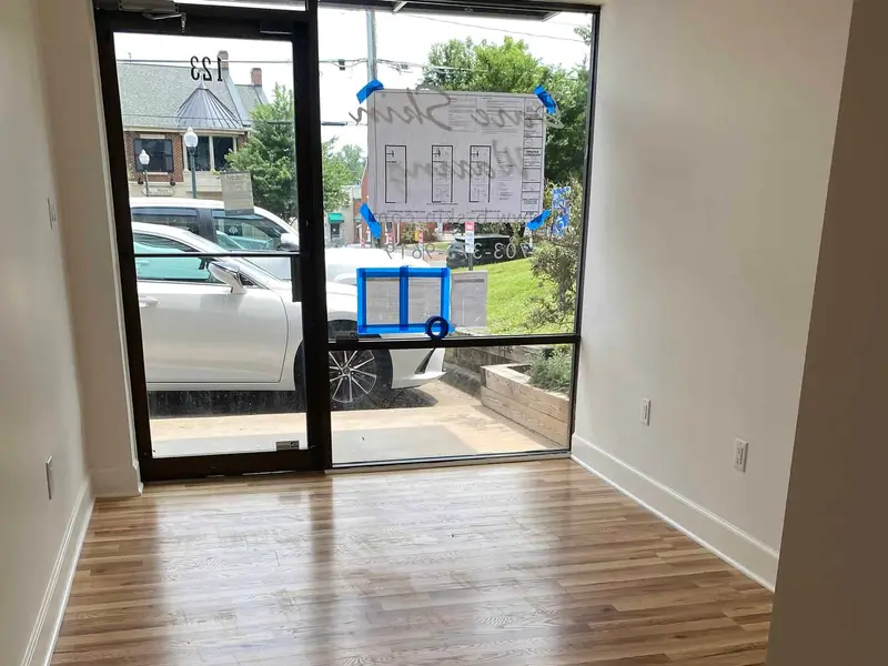 Finished salon suite with light wood flooring, glass door, and fresh paint