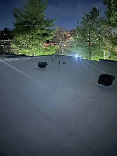 New white TPO membrane roof on a multi-family building at night with rooftop vents and exterior lighting