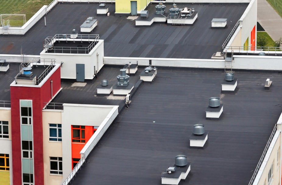 Aerial view of a modern building with flat rooftop ventilation systems and colorful facade elements, ideal for commercial renovation services.
