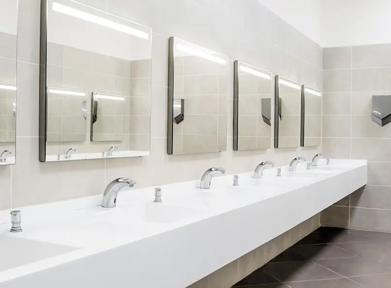 Public restroom remodel with five sinks and mirrors, tiled walls, modern design.