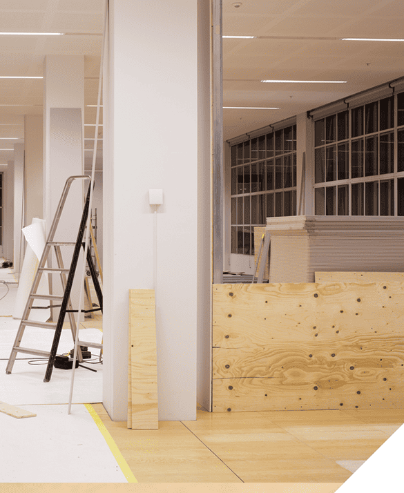 Office renovation in progress with ladder, plywood sheets, and construction materials neatly arranged. Interior remodel concept for enhanced workspace.