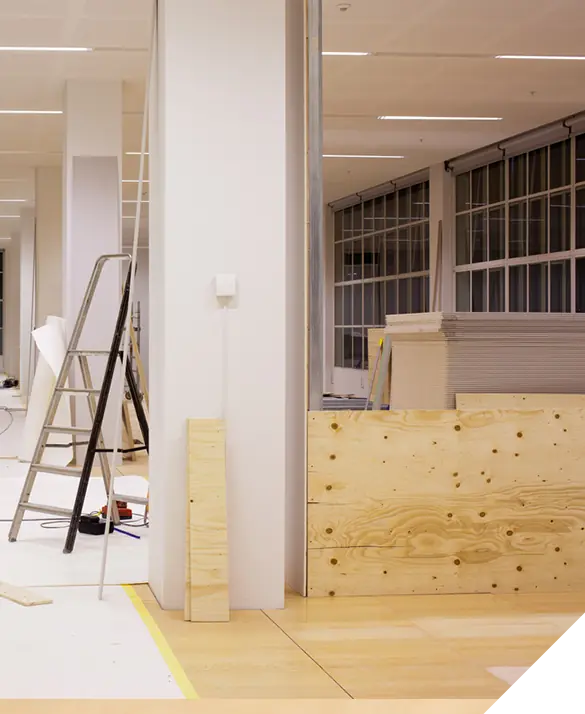 Office renovation in progress with ladder, plywood sheets, and construction materials neatly arranged. Interior remodel concept for enhanced workspace.