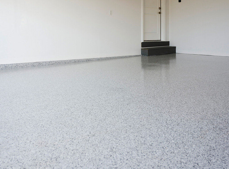 Empty room with light gray epoxy flooring, pristine white walls, door, and small steps—perfect for versatile commercial renovation and construction projects.