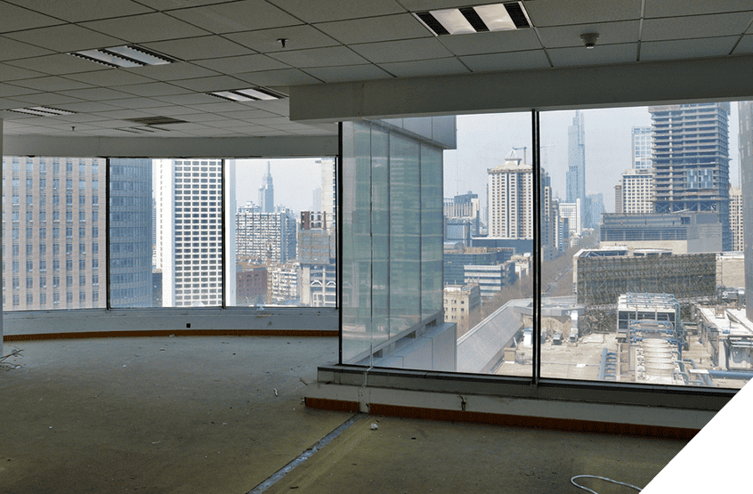 Spacious office space with large windows, skyline view of city skyscrapers, cloudy sky backdrop, exposed flooring, ceiling lights; ideal setting for commercial glass repair business.