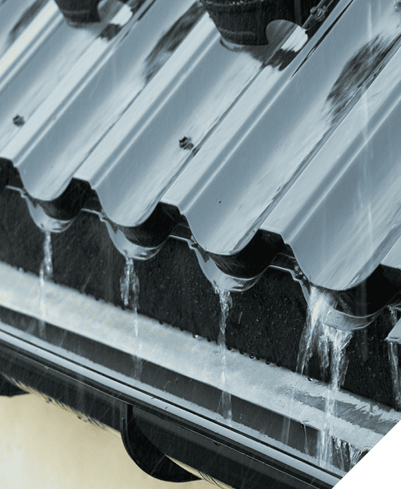 Close-up of rainwater flowing off a corrugated metal roof into a gutter, highlighting expert siding and gutter installation.