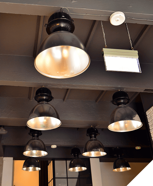 Industrial-style ceiling with pendant lights and rectangular fixture suspended from metal beams, perfect for commercial lighting solutions.