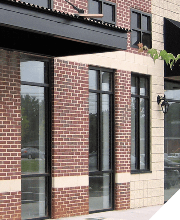 A storefront with expertly installed glass windows and classic red brick facade, showcasing quality exterior renovation work.
