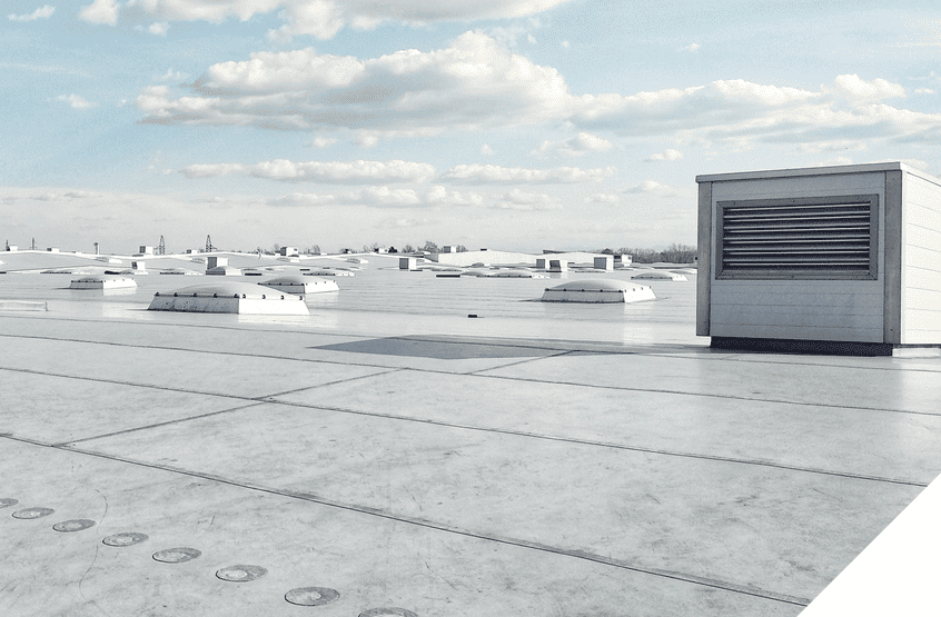 Flat industrial rooftop with skylights and vent, under partly cloudy sky, ideal for expert roofing and renovation services.