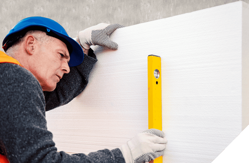 Construction worker wearing blue helmet and orange vest expertly uses yellow level on white panel in exterior remodeling process.