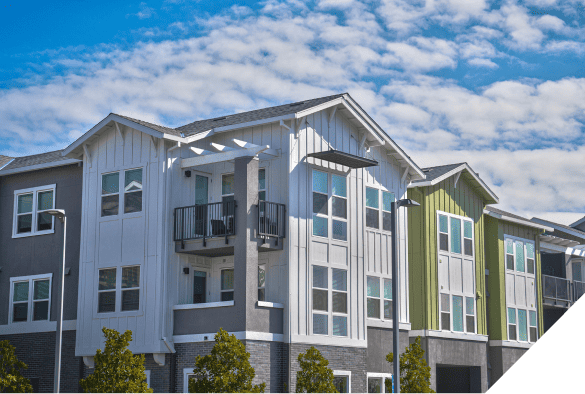 Modern apartment building with white and green panels, expansive balconies, and large windows against a partly cloudy sky. Ideal for exterior and interior renovation inspiration.