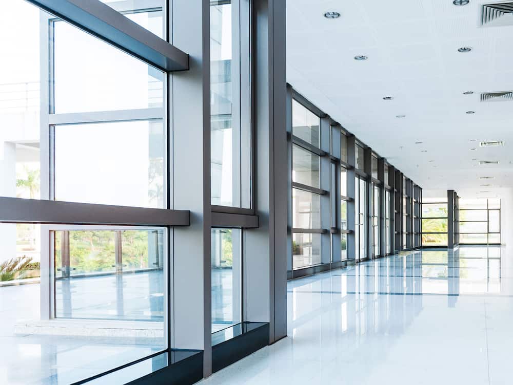 Modern hallway with large window installation, bright natural lighting, reflective flooring, stylish building interior renovation.