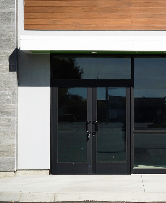 Modern wood and stone facade with dark glass double door entrance, exemplifying expert exterior renovation and door installation.