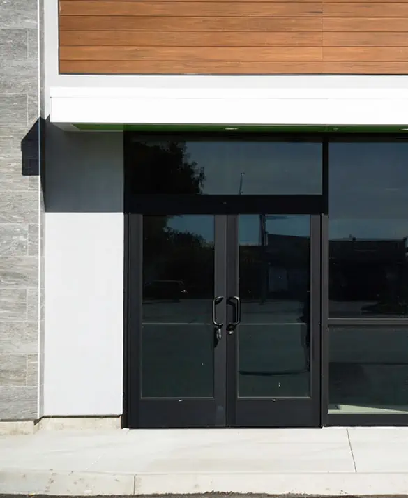 Modern wood and stone facade with dark glass double door entrance, exemplifying expert exterior renovation and door installation.