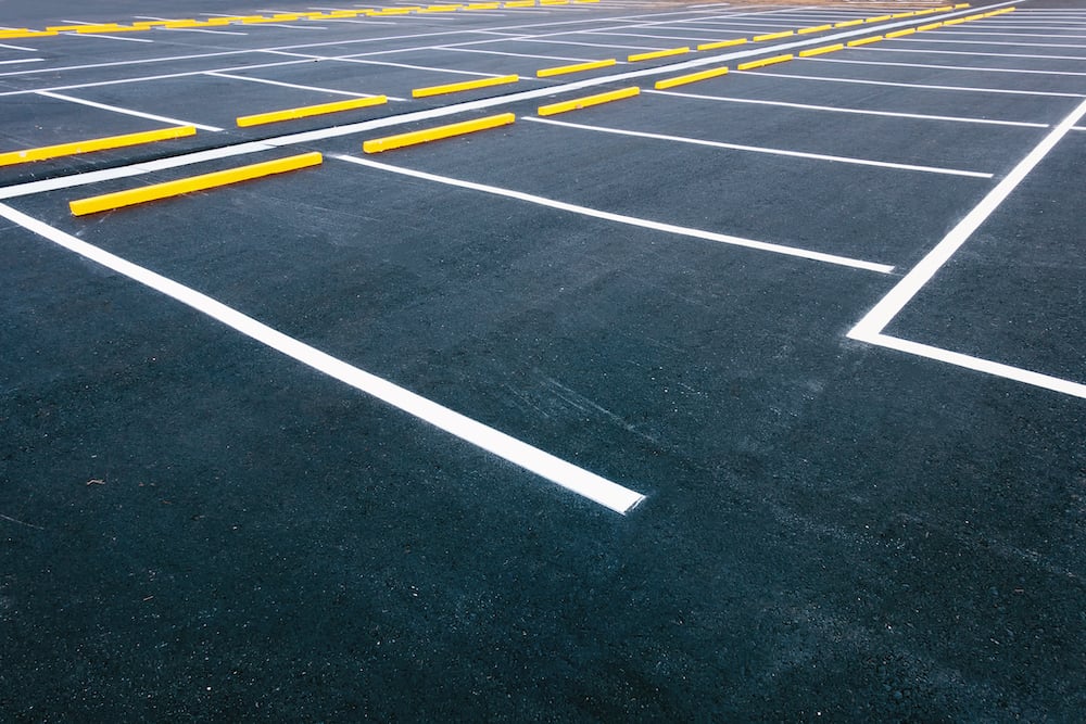 freshly painted white lines yellow wheel stops dark asphalt precision parking lot renovation services