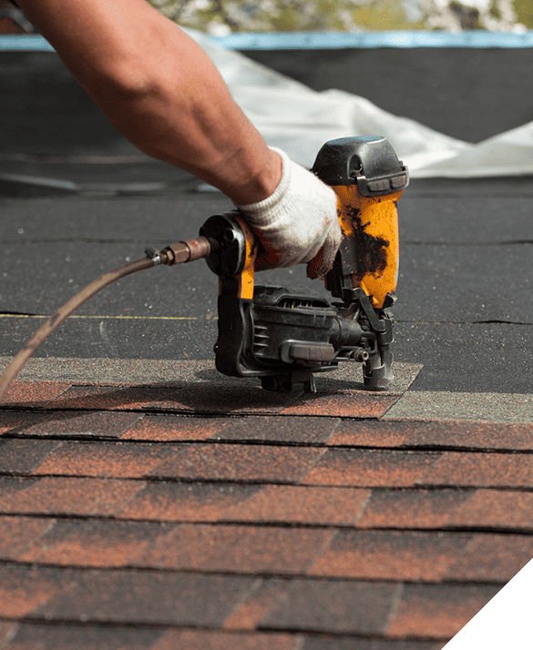 Expert roofer using a pneumatic nail gun to secure shingles, demonstrating professional roofing services.