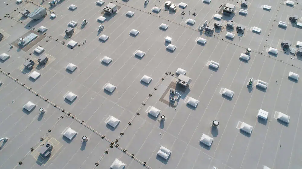 Large commercial roof covered in singl-ply roofing with skylights and HVAC units