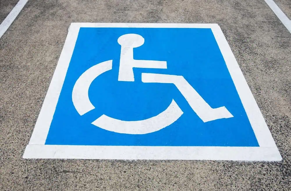 Disabled parking symbol in blue and white on asphalt near commercial roofing renovation, Bethesda.