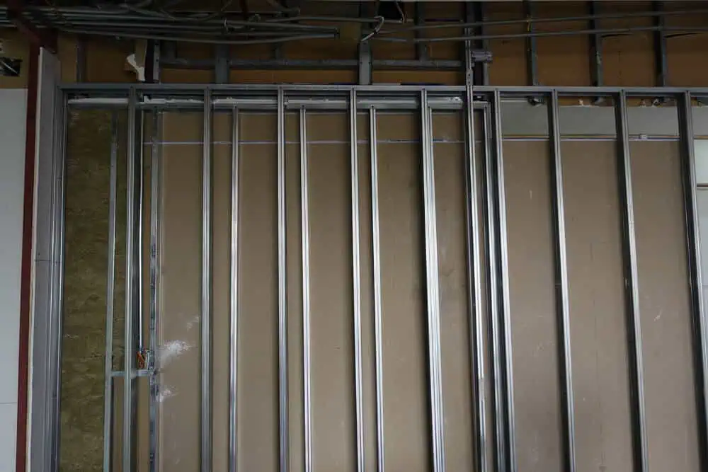 Vertical metal studs installation in partially built wall showing exposed wiring; essential step in interior renovation and construction services.