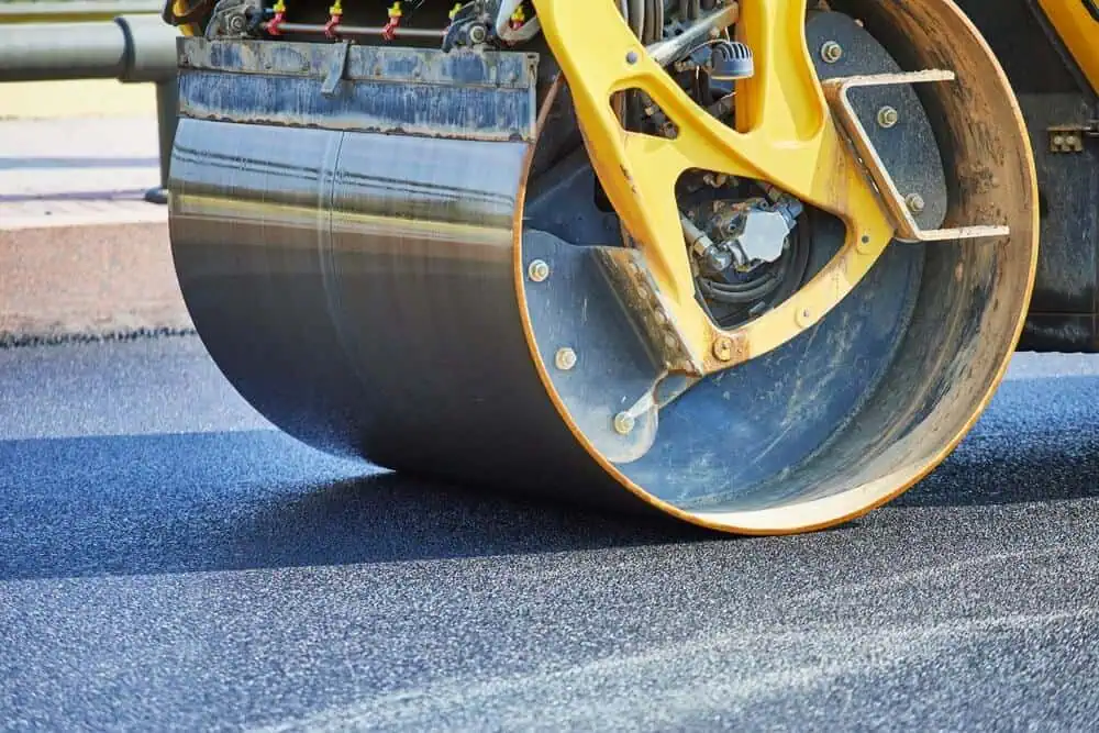 A pavement roller smoothing fresh blacktop in a parking lot
