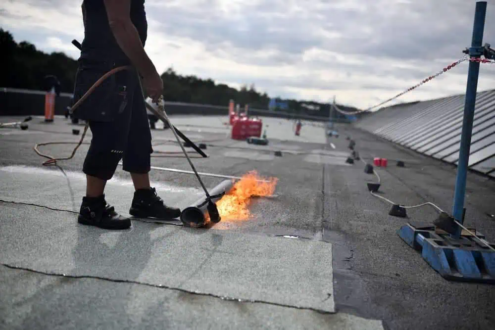 A worker applies a roofing patch to a commercial roofing membrane
