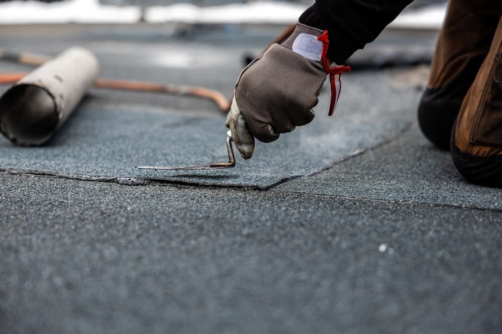 A roofer installing a commercial roofing patch with trowel