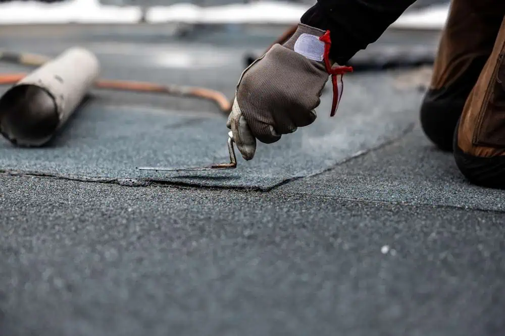 A roofer installing a commercial roofing patch with trowel
