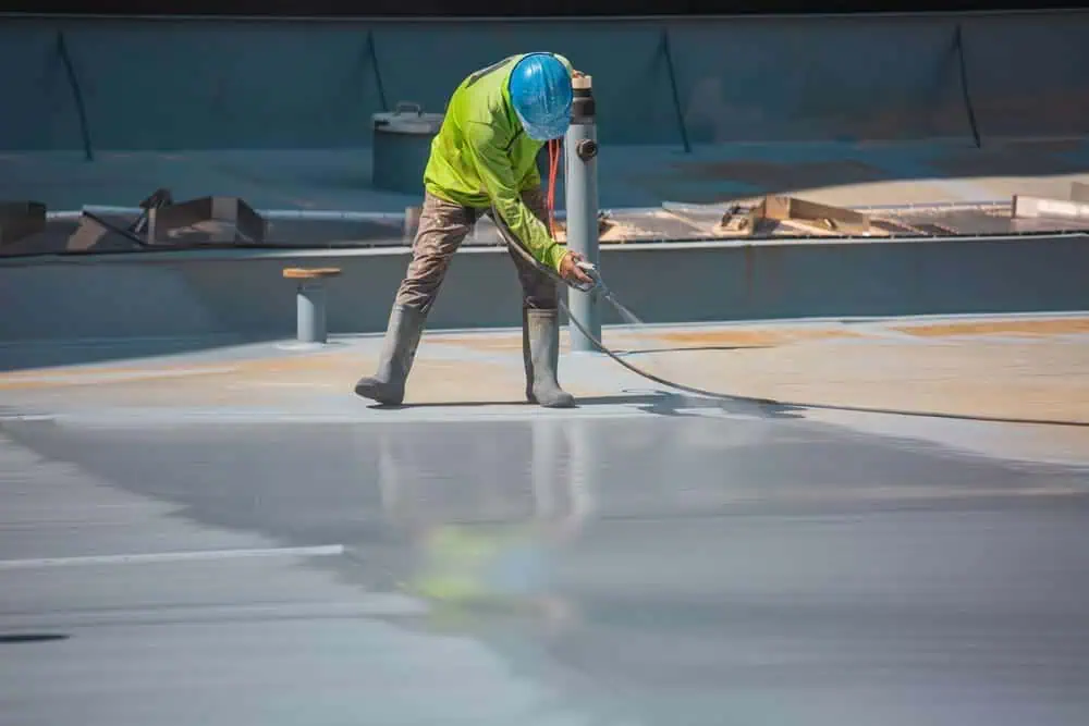 Worker applying a commercial roof restoration coating